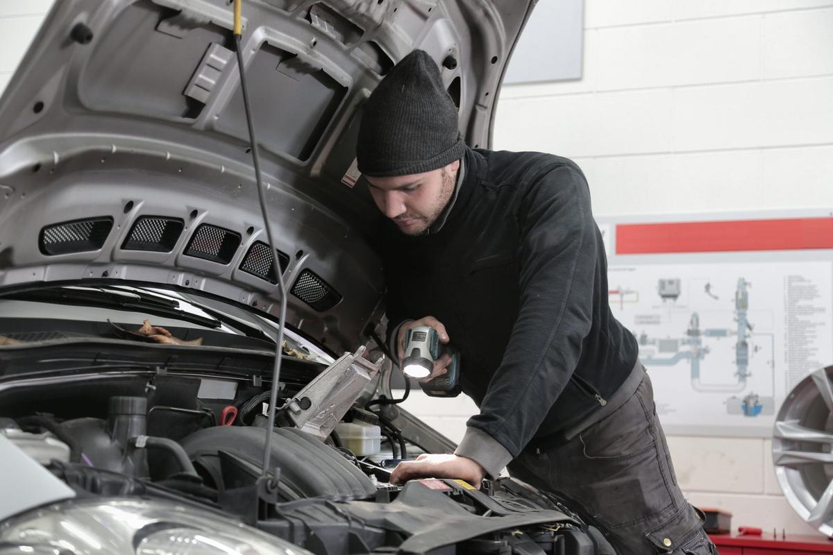 Technician checking an engine bay with a flashlight